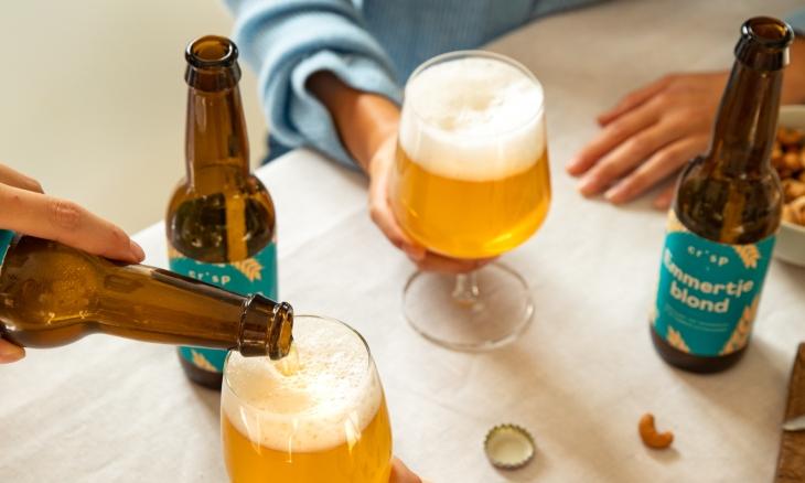Crisp Emmertje Blond bier glazen en flesjes op tafel terwijl een glas wordt volgeschonken
